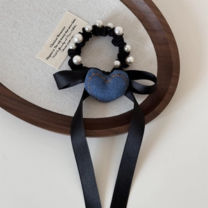 Dettaglio dell'elastico vintage in denim con perle ed eleganti lunghi nastri di raso nero