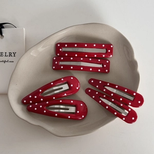 Detailed set of red hair clips with white polka dots in various geometric shapes