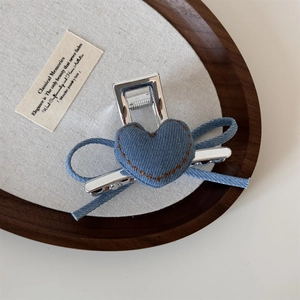 Dettaglio della molletta per capelli in denim blu con cuore e fiocco su vassoio