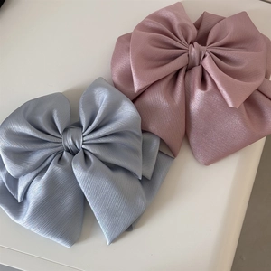 Detailed macro view of large multi-layer satin bow hair clips in pink and silver-blue