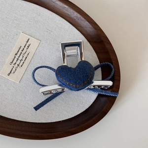 Dettaglio macro di un fermaglio per capelli in denim a forma di cuore su vassoio