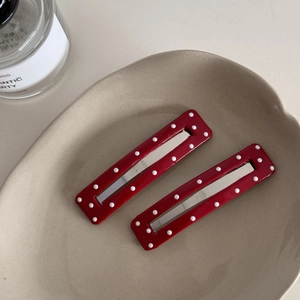 Detail of red rectangle hair clips with white polka dots on a beige ceramic tray