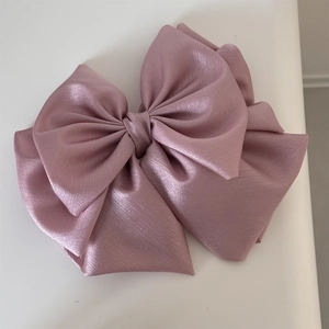 Macro view of a large multi-layer satin bow hair clip in dusty rose with subtle silk texture