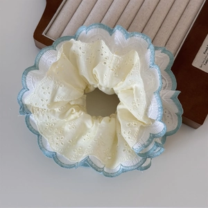 Close-up of mint green lace scrunchie with intricate floral embroidery and wavy edging