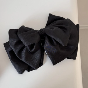 Detail of classic black satin bow hair claw clip with multi-layered fabric texture