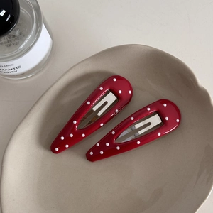 Close-up of red polka dot hair clips with metallic clips in a decorative ceramic dish
