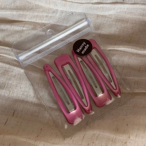 Detail of four rose pink metallic water drop hair clips in professional retail packaging