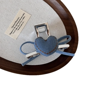 Pinza per capelli vintage in denim azzurro con fiocco a cuore e cuciture marroni su vassoio