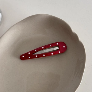 Detailed close-up of a red polka dot leather hair clip resting on a ceramic tray