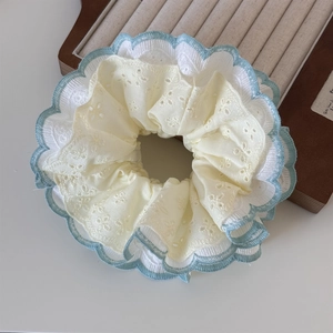 Detailed macro view of mint green floral embroidery and white lace on fabric scrunchie