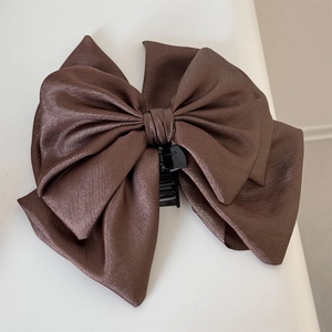Close-up of a large brown satin bow hair claw clip with detailed twill fabric texture
