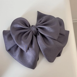 Detail of multi-layered bow hair clip with shimmering satin fabric in deep greyish purple