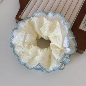 Detailed close-up of mint green lace embroidery and floral fabric on a scrunchie