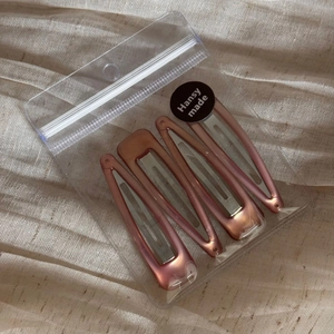 Detailed view of four rose gold metallic BB hair clips in clear packaging with a brand label