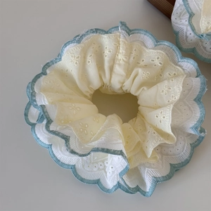 Detailed macro view of mint green double-layer lace scrunchie with blue wavy edges