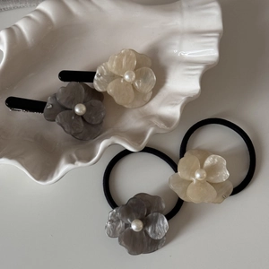 Elegant acetate flower hair clip set with pearls and rhinestones on a stylish ceramic plate
