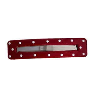 Red leather hair clip with white polka dots and silver metal snap on white background