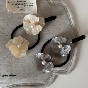 Detailed close-up of acetate flower hair clips and elastic bands with pearls and rhinestones