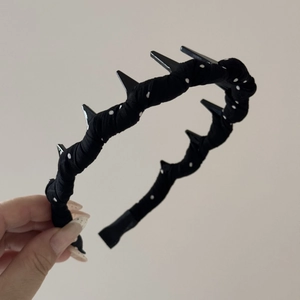 Détail du serre-tête à pois avec pointes punk noires et finition en tissu texturé