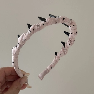 Vue détaillée du serre-tête en tissu rose à pois avec dents intérieures pour fixer la coiffure