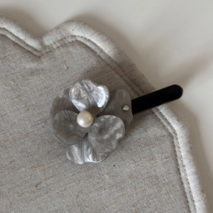 Detailed close-up of a floral acetate hair clip with grey marble texture and a center pearl