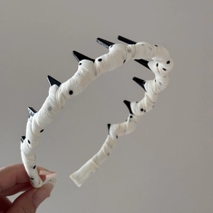 Détail d'un serre-tête français à pois avec dents antidérapantes et ruban en tissu blanc