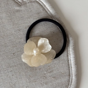 Detailed macro of a cream acetate flower hair clip with a centered glossy pearl bead