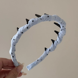 Détail du serre-tête bleu à pois avec pointes décoratives noires et texture de tissu doux