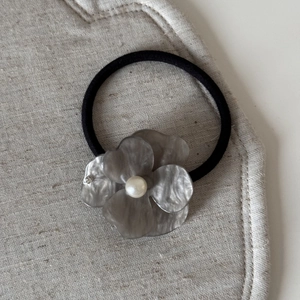 Detailed macro shot of a gray acetate flower hair clip with pearl and rhinestones decoration
