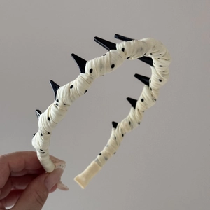 Détail montrant les dents antidérapantes et le tissu beige à pois du serre-tête