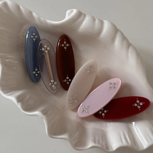 Detailed close-up of six colorful resin oval hair clips with sparkling rhinestone accents