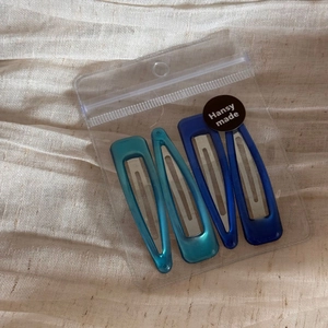 Detail view of 4-piece translucent resin BB hair clips in blue and teal with pearly luster
