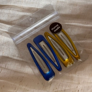 Detail view of four-piece blue and yellow teardrop hair clips in clear packaging