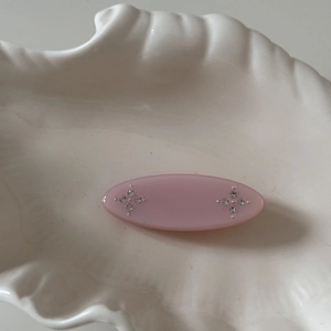 Detail of pink resin hair clip with small rhinestones on a decorative shell plate
