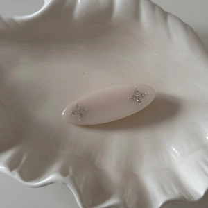 Close-up of a nude pink oval hair clip with sparkling rhinestones on a ceramic dish