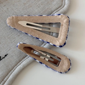 Detail showing back construction of blue checkered hair clips with silver metal ducks bill