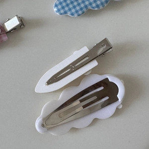 Détail des pinces à bec de canard en métal et du support blanc des barrettes à carreaux