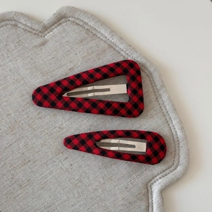 Detail view of red and black checkered fabric hair clips in triangle and oval shapes