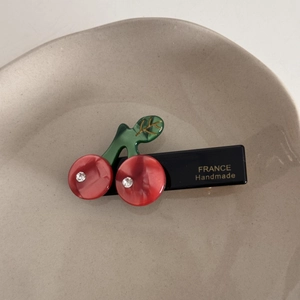Détail d'une pince à cheveux cerise faite main avec résine rouge et strass brillants
