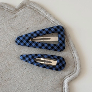 Detail of blue and black checkered fabric hair clips in triangle and oval shapes