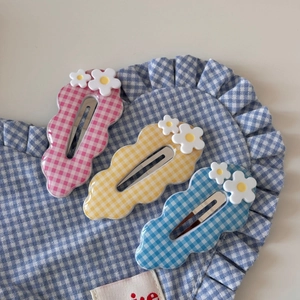 Gros plan détaillé de barrettes à carreaux roses, jaunes et bleues avec de petites marguerites