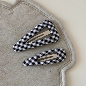 Detailed macro view of black and white checkered fabric pattern on the pair of BB hair clips