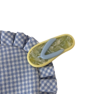 Haarklammer aus Acetat in Flip-Flop-Form mit Marmormuster auf blau kariertem Stoff