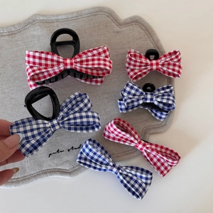 Dettaglio di fermagli per capelli con fiocco a quadretti rossi e blu in stile British