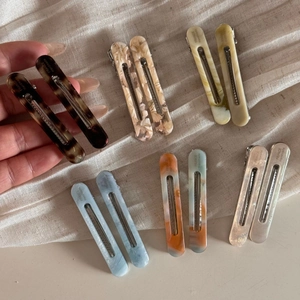 Minimalist acetate hair clip set with tortoiseshell and marble patterns on textured fabric