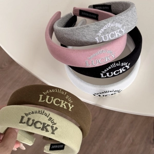 Detail of LUCKY embroidered letters on high crown sponge headbands in various colors