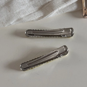 Detailed macro view of silver metal duckbill hair clips with cream acetate inlay