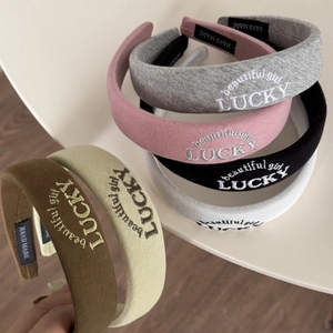 Detail of LUCKY embroidered padded headbands with handmade tags in various colors