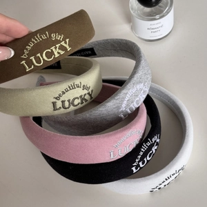 Detail of LUCKY embroidered headbands showing assorted colors and handmade labels