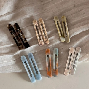 Flat lay of acetate hair clip set with marble patterns on a textured linen fabric